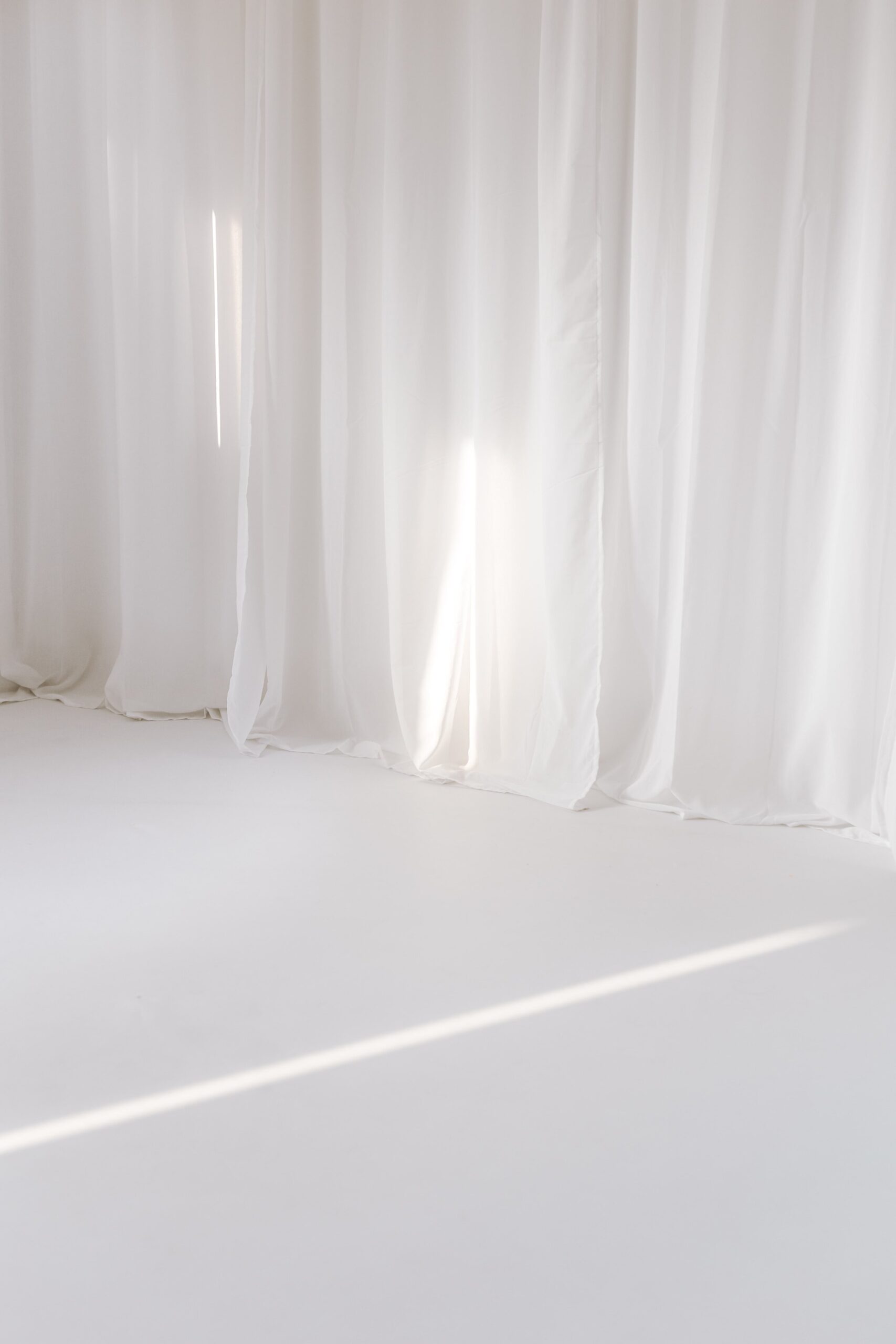 Ausschnitt eines Fotostudios mit weißem Boden und weißen Gardinen.